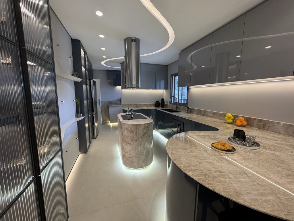 Imagem de um apartamento em Guarulhos, o decorado do empreendimento tecnológico Horizon, uma cozinha moderna, com formas orgânicas, luz indireta, detalhes em mármore e vidro